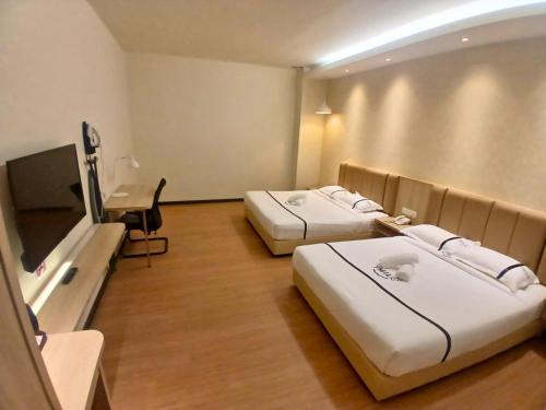 a hotel room with two beds and a desk at Seeds Hotel Premier The Mines Seri Kembangan in Seri Kembangan