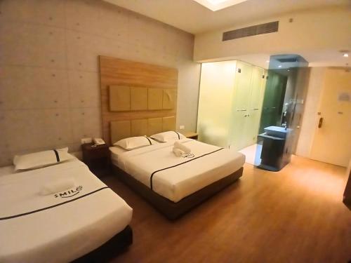 a hotel room with two beds and a hallway at Seeds Hotel Premier The Mines Seri Kembangan in Seri Kembangan