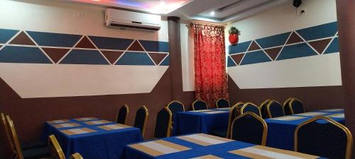 a room with blue tables and chairs and a wall at chikays plaza in Trofwi