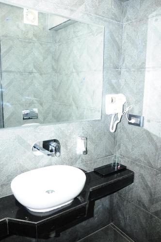 a bathroom with a white sink and a mirror at Vgrand in Ooty