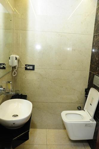 a bathroom with a white toilet and a sink at Vgrand in Ooty