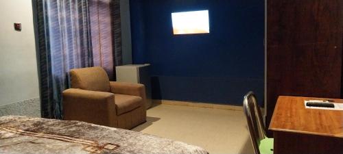 a room with a chair and a table and a window at chikays plaza in Trofwi