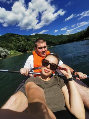 a man and a woman in a boat on the water at Apartmani Kriva Drina in Okletac