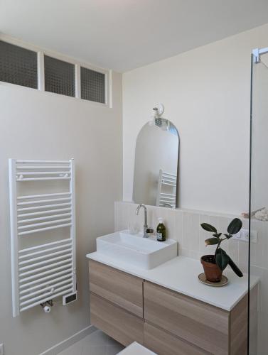 une salle de bain blanche avec un lavabo et un miroir dans l'établissement Korrigan Cove maison 8 personnes Saint Benoit, à Saint-Benoît-des-Ondes