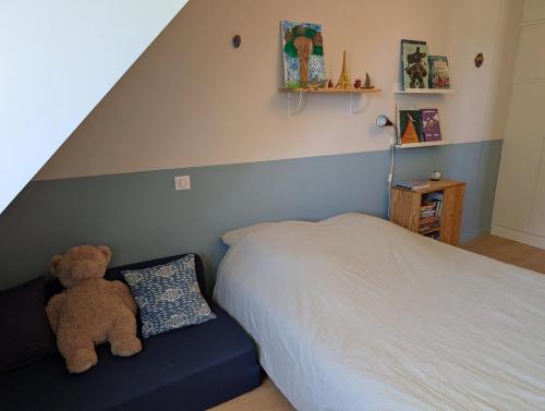 a teddy bear sitting on a bed in a bedroom at Korrigan Cove maison 8 personnes Saint Benoit in Saint-Benoît-des-Ondes