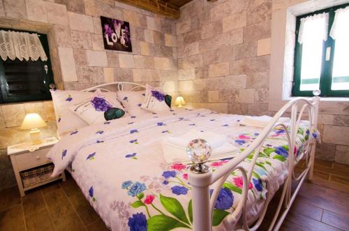 a bedroom with a white bed with flowers on it at House Radojka in Tisno