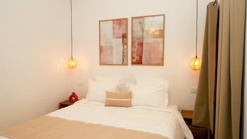 a bedroom with a bed with white sheets and two lights at Riad Reflet D'orient Marrakech in Marrakech
