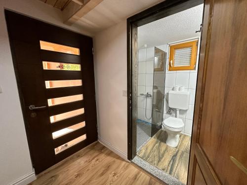 a bathroom with a toilet and a glass door at Stanetestruzhes in Prizren