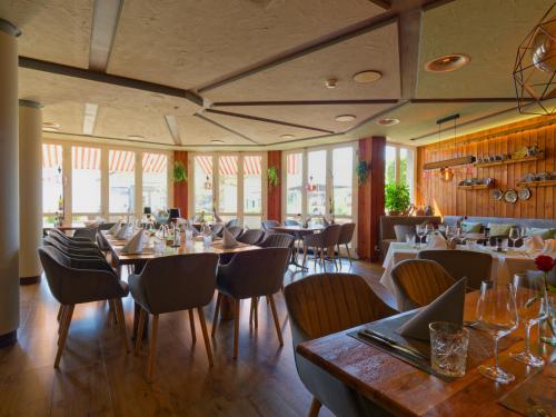 a restaurant with wooden tables and chairs and windows at Seehotel Riviera at Lake Lucerne in Gersau