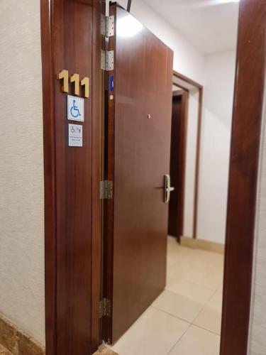 a wooden door with a sign on it in a hallway at Sarwat Park Hotel Riyadh - Diplomatic Quarter in Riyadh