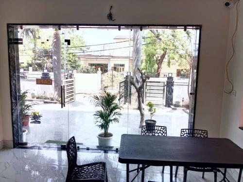 范兰德凡Hotel Dev Shri Residency ! near Prem mandir & ISCKON ! Fully AC rooms ! Café & Banquet, Free parking & Lift availability的配有大窗户的客房内的桌椅