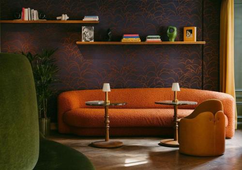 an orange couch in a living room with two tables at Hôtel De Buci in Paris