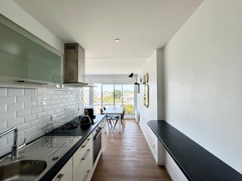 une cuisine avec des murs blancs et un comptoir noir dans l'établissement Appartement rénové vue mer, Bénodet, à Bénodet
