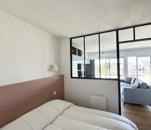 - une chambre avec un lit, un canapé et des fenêtres dans l'établissement Appartement rénové vue mer, Bénodet, à Bénodet