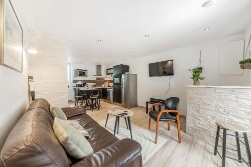 un salon avec un canapé marron et une cuisine dans l'établissement L'Amadea - Duplex - 3 pers au coeur de Parame, à Saint-Malo