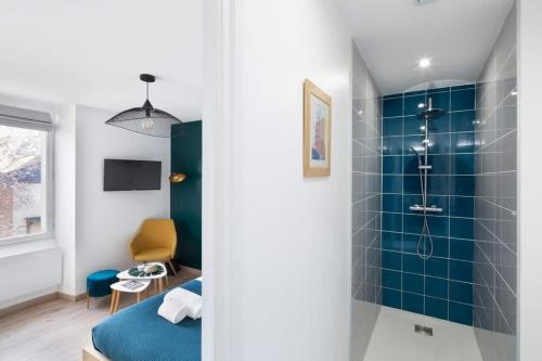 La salle de bains est pourvue d'une douche et d'un mur en carrelage bleu. dans l'établissement L'éden studio moderne et lumineux proche centre, à Rennes