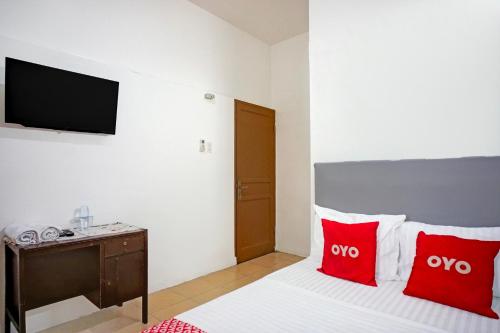 a bedroom with a bed with red pillows and a tv at Hotel O Medan near Universitas Sumatera Utara formerly Surya Residence in Sunggal