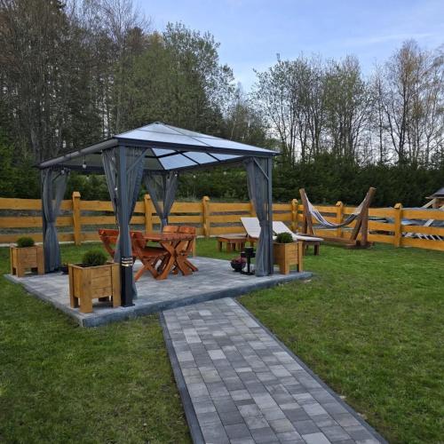 a picnic shelter with a picnic table and benches at Domek na Czerwonej Górce in Uście Gorlickie