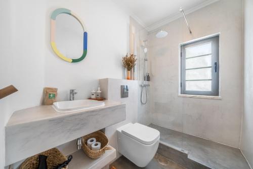 Un baño con lavabo, inodoro y espejo. en Casa Ela Navega, en Aljezur