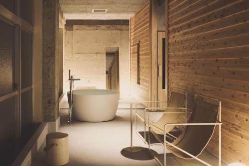 a bathroom with a tub and two chairs at mizuya in Miyazu