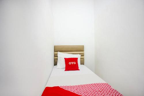 a red pillow on a bed in a white room at Hotel O Medan near Universitas Sumatera Utara formerly Surya Residence in Sunggal
