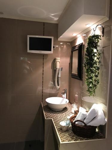 a bathroom with a sink and a tv on the wall at Hotel Cosy Bouillon in Bouillon