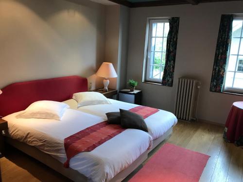 a bedroom with a large bed with a red headboard at Hotel Cosy Bouillon in Bouillon