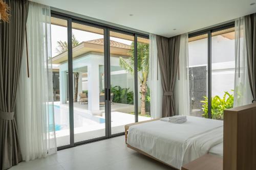 a bedroom with a bed and a large window at Mouana Breeze Mai Khao 4-bedroom Pool Villa 9925 in Mai Khao Beach