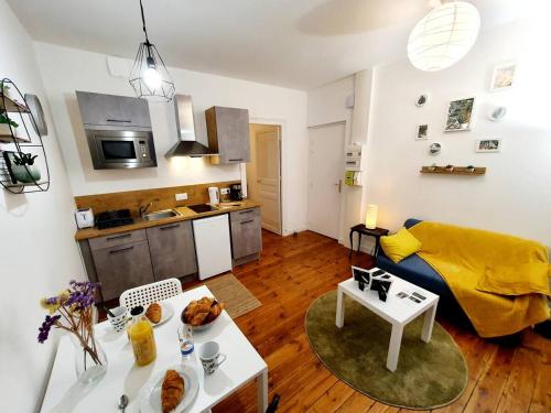 un soggiorno con divano, tavolo e cucina di Le Erquy - Proche gare et centre. a Saint-Brieuc