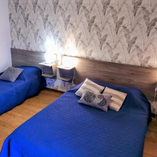 - 2 lits dans une chambre avec des draps et des oreillers bleus dans l'établissement Gite Les Renardières en Bretagne Romantique proche, à Saint-Pierre-de-Plesguen