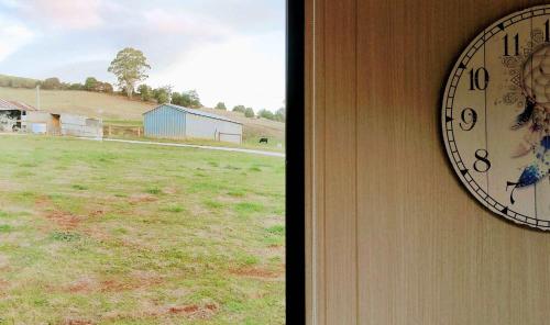 a clock on the side of a house with a field at Perrys North by Tiny Away in Forth