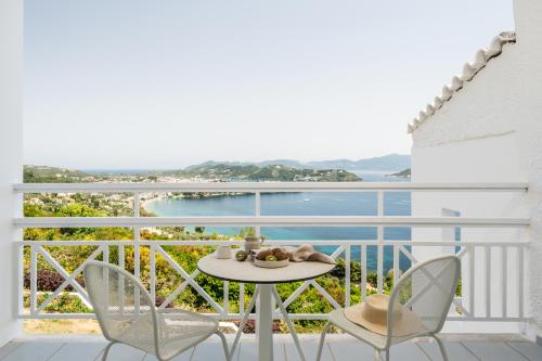 a table and chairs on a balcony with a view of the water at Oniro Skiathos in Skiathos Town