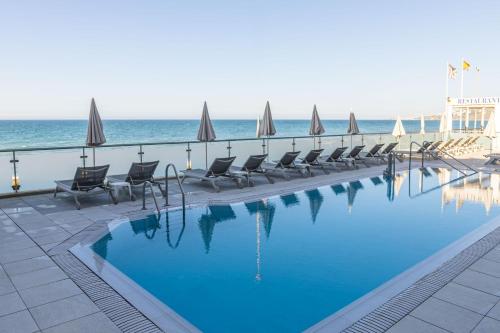 a swimming pool with chairs and umbrellas next to the ocean at Perla Marina in Nerja