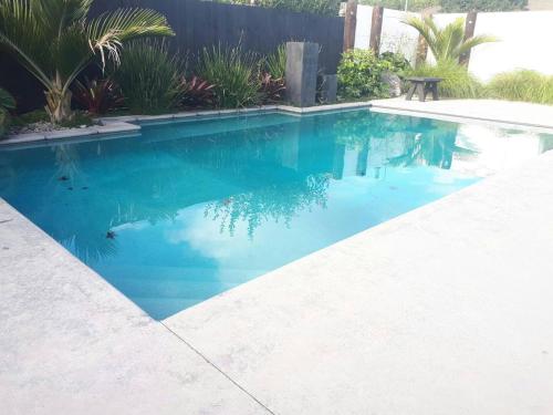 a swimming pool with blue water in a yard at Bethlehem Home, plus Self Contained Apartment in Tauranga