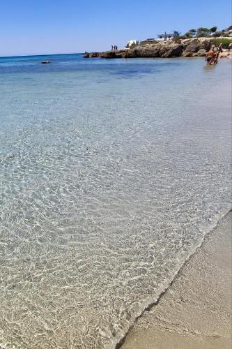 a beach with a body of water with rocks in the background at WalMarhouse in Taranto