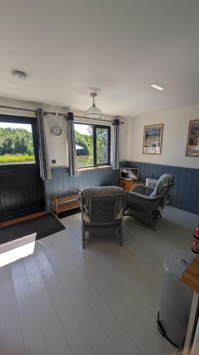 a living room with chairs and a couch and windows at Lynstone Lakes in Bude
