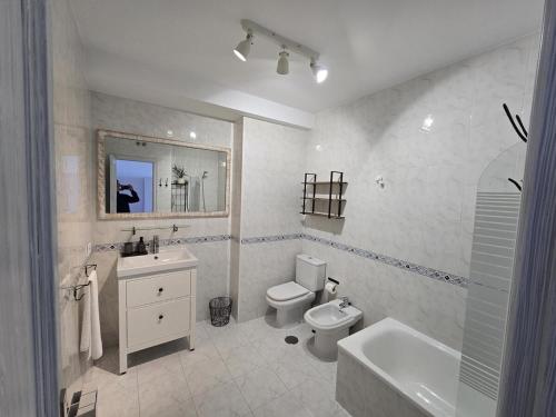a white bathroom with a toilet and a sink at Winahost Vionta en Primera Línea de Mar in Ribeira