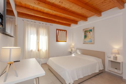 a white bedroom with a white bed and a desk at B&B Pettirosso in San Teodoro