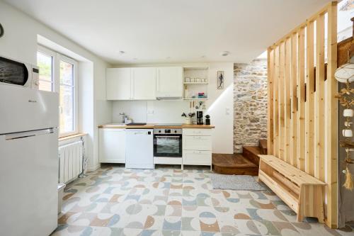 une cuisine avec des placards blancs et un escalier dans l'établissement La Maison Valnotte - Proche du port de Carteret, à Barneville-Carteret