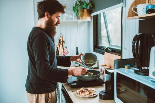 a man is preparing food in a kitchen at River Ridge Tiny House by Tiny Away in South Arm