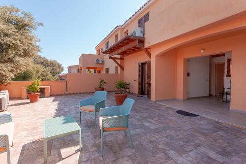 a patio with chairs and tables and a building at B&B Pettirosso in San Teodoro