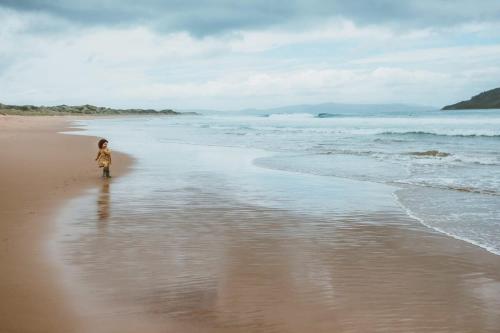 a young child walking on the beach at River Ridge Tiny House by Tiny Away in South Arm