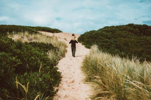 a woman walking down a path in the sand at River Ridge Tiny House by Tiny Away in South Arm
