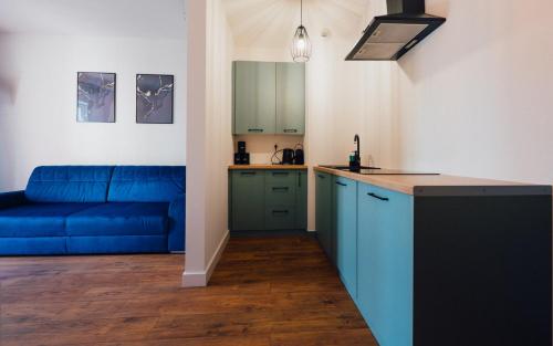 a living room with a blue couch and a kitchen at AboutArtApartments - By the river in Wrocław