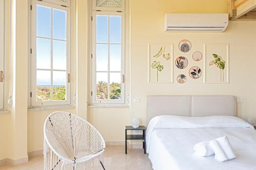 a bedroom with a bed and a chair and windows at Homiday -Gioiello Vista Mare- Parcheggio Privato in Calambrone