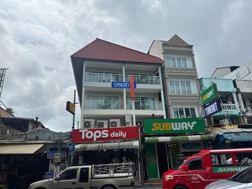a building on a city street with cars parked in front at Sparta Patong in Ban Nong Chaeng