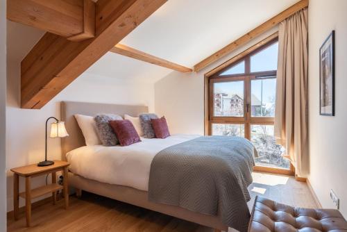 une chambre avec un lit et une grande fenêtre dans l'établissement Apartment Ecrin Alpe d'Huez - BY EMERALD STAY, à Huez