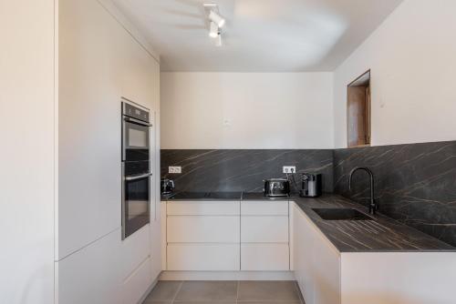 une cuisine avec des armoires blanches et un comptoir noir dans l'établissement Apartment Ecrin Alpe d'Huez - BY EMERALD STAY, à Huez