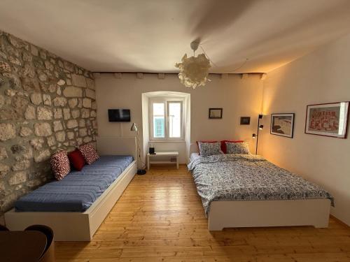a bedroom with two beds and a stone wall at Apartment Naval in Dubrovnik