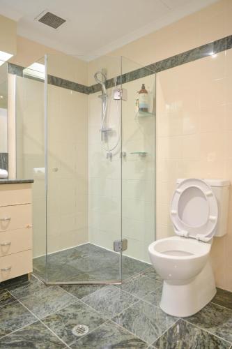 a bathroom with a toilet and a glass shower at Modern Darling Harbour 2BR Apt Walk to Everything in Sydney